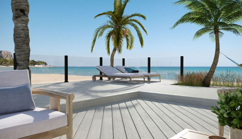 Luxury glass infilled railing on a deck that is sitting on a beach.
