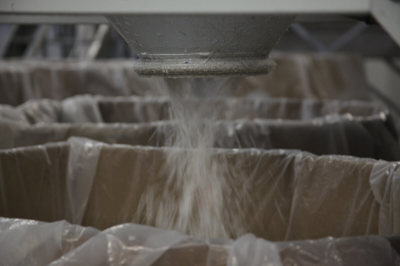 Shredded plastic material falling out of the shredding machine into a box.